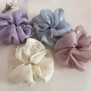 Vue à plat de chouchous en organza coloré avec broderie florale aux tons pastel