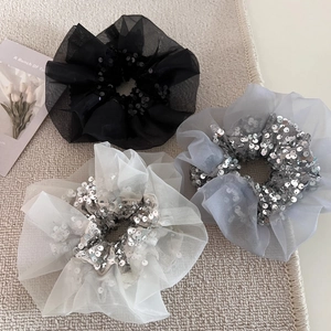 Detail of three organza scrunchies with sequins in black, grey, and cream colors