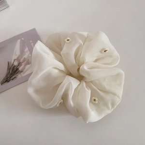 Détail du chouchou en organza blanc crème avec de délicates broderies florales