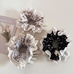 Detailed macro view of three floral scrunchies with white lace edges on a clean background