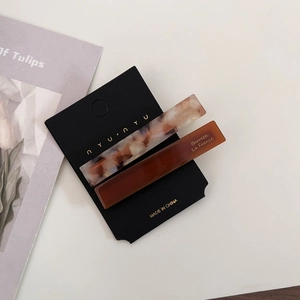 Close-up of tortoise shell and marble acetate hair clips on a black brand card