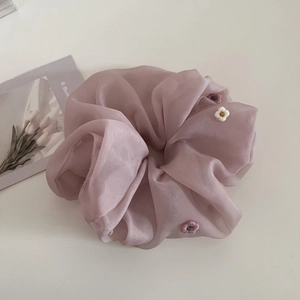 Détail d'un chouchou en organza rose avec broderie florale délicate et texture fine