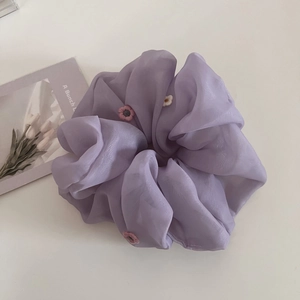 Détail d'un chouchou en tulle violet avec de délicates broderies florales roses