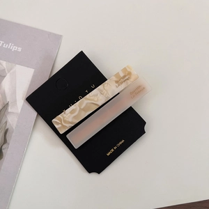 Detailed macro view of two marble acetate hair clips with gold lettering on black card