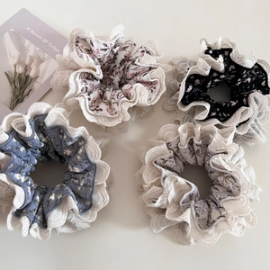 Set of four floral fabric scrunchies with double-layer white lace edges on white background