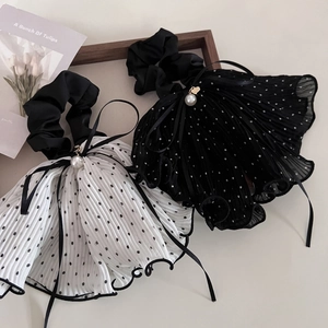 Dettaglio di scrunchie plissettato a pois con nastri lunghi, fiocco e perla