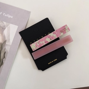 Detail of two-piece pink marbled acetate hair clips set on a branded display card