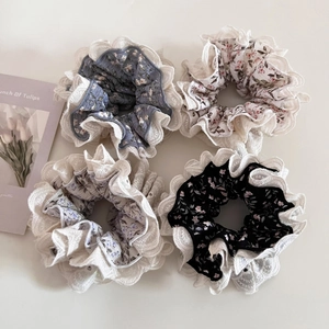 Close-up of floral hair scrunchies with white lace edges in various pastel colors
