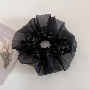 Detail view of large black organza scrunchie with shiny sequins on white background