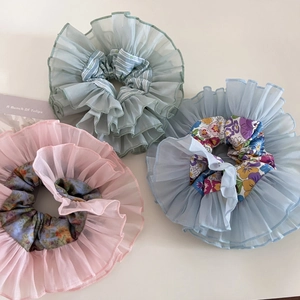 Detailed macro view of three double-layer organza floral scrunchies in pastel colors