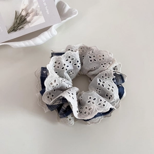 Close-up of double-layered blue plaid scrunchie with white lace embroidery and heart pattern