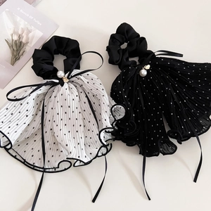 Dettaglio di elastici per capelli in tulle a pois con perle e ciondoli a cuore