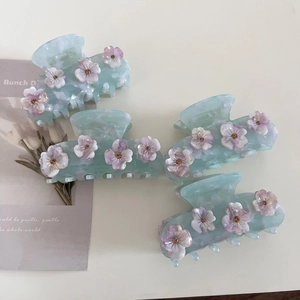 Dettaglio di quattro mollette per capelli in acetato azzurro con fiori 3D sfumati