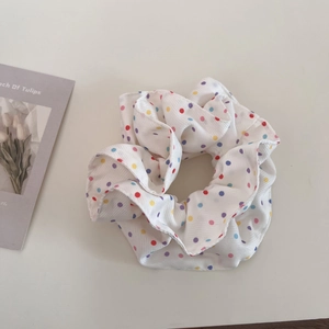 Detail of white scrunchie with colorful polka dots showing fabric texture and vibrant pattern