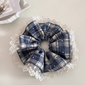 Detailed view of a blue plaid scrunchie with white lace edges and heart patterns