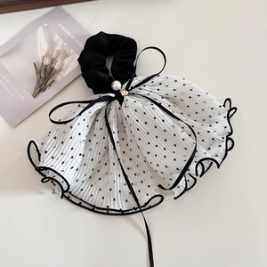Dettaglio dell'elastico in chiffon a pois con perla bianca e ciondolo a cuore dorato