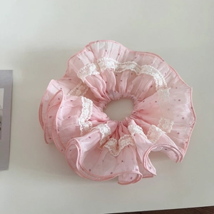Détail d'un chouchou en maille rose avec bords en dentelle et pois délicats