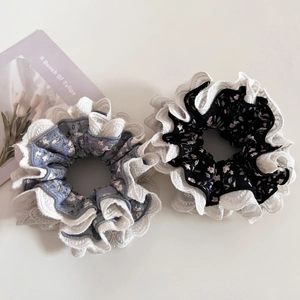 Detail of blue and black floral scrunchies with white lace trim on a white background