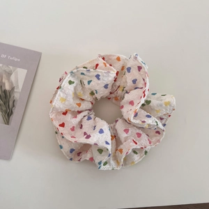 Detail of white scrunchie with multi-colored heart patterns and textured fabric