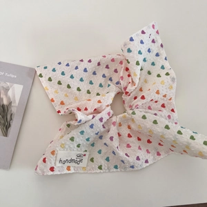 Close-up of waffle texture scrunchie with colorful hearts and a handmade fabric label