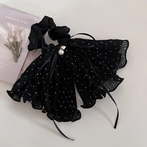 Dettaglio dell'elastico per capelli nero a pois con lunghi nastri e perla