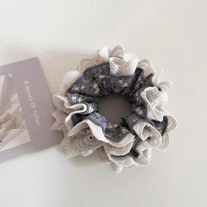 Detail of floral scrunchie with layered lace edges and retro purple pattern design