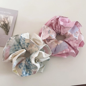 Gros plan de chouchous floraux aux motifs roses et bleus sur fond blanc épuré