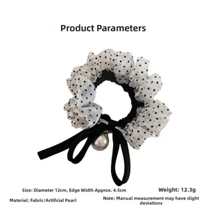 Detailed view of polka dot scrunchie with a black ribbon bow and artificial pearl charm