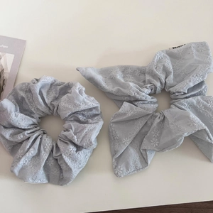 Detail of light blue linen scrunchie set with white floral embroidery and ribbon bows