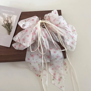 Détail d'une pince à cheveux avec nœud en mousseline florale et rubans multicouches