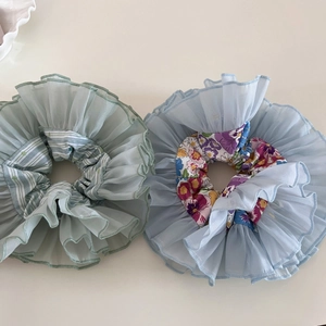 Detail view of layered organza floral scrunchies in bean green and light blue styles