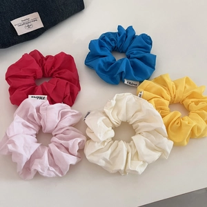 Gros plan de cinq chouchous colorés en coton avec des coutures soignées et de petites étiquettes