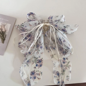 Vue détaillée de la pince à cheveux en mousseline fleurie violette avec rubans blancs