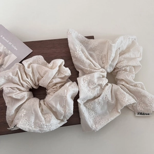 Detailed macro view of cream linen hair scrunchies with floral embroidery and bow knot