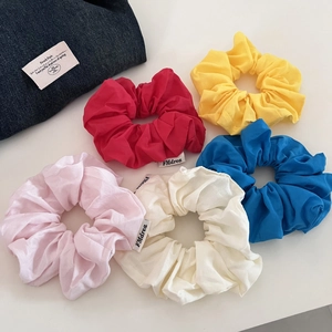 Lot de cinq chouchous en coton coloré avec texture naturelle et étiquettes de marque