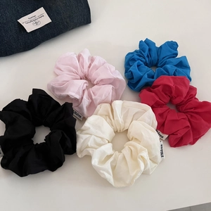 Détail de cinq chouchous en coton multicolores avec des plis élégants et étiquettes en tissu