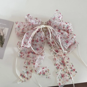 Détail d'une grande pince à cheveux en mousseline avec nœud et motifs floraux roses