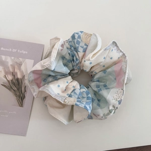 Détail d'un chouchou floral avec motifs à carreaux bleus et pois roses sur blanc