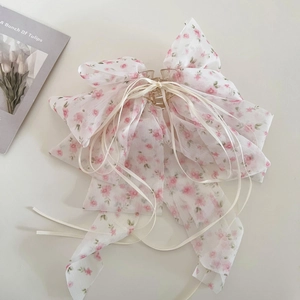 Détail de la pince à cheveux noeud en mousseline fleurie avec de longs rubans