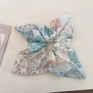 Détail du chouchou patchwork à fleurs bleues avec des motifs à carreaux et géométriques