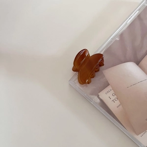Detail of amber brown acetate hair claw clip on a minimalist display with soft lighting
