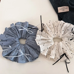 Close-up of pleated beige and blue polka dot scrunchies with elegant bow details