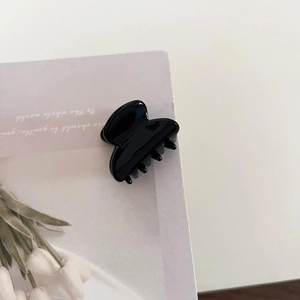 Detailed view of a glossy black acetate hair claw clip with a secure interlocking tooth design