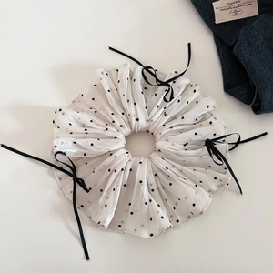 Macro detail of beige polka dot organza scrunchie with a delicate black ribbon bow