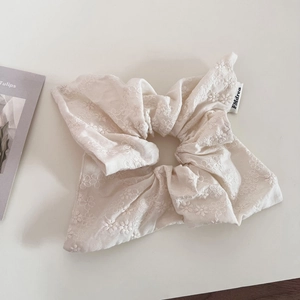 Detail of cream cotton hair scrunchie with floral embroidery and brand woven label