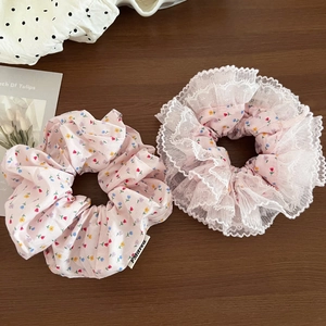 Floral hair scrunchies set with white lace trim detail on a brown wooden background