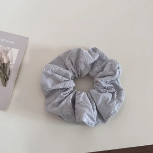 Detailed view of soft cotton scrunchies featuring fine white floral embroidery and texture