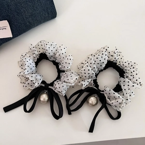 Macro view showing polka dot organza scrunchies with black satin bow and large pearl detail