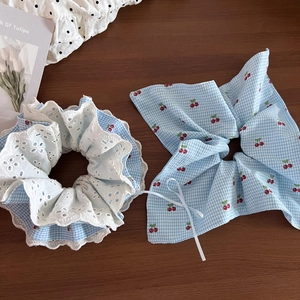 Detailed view of checkered cherry print bow and lace scrunchie set on wood surface