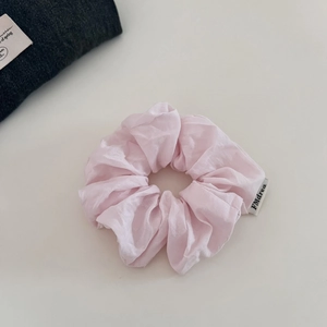 Vue détaillée du chouchou en coton rose clair avec étiquette de logo et texture douce